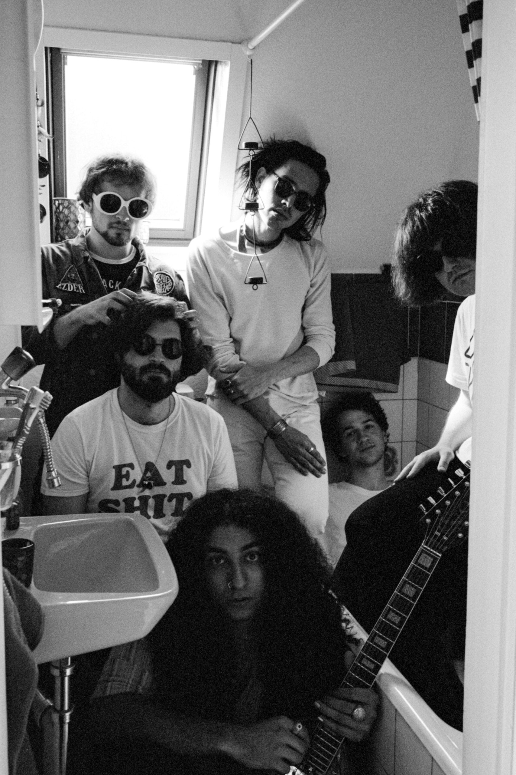Members of a band posing in a small bathroom.